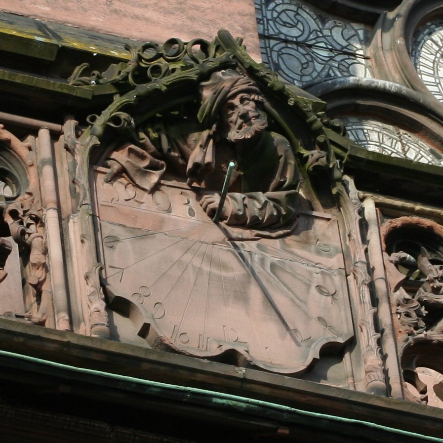 Sonnenuhr mit Polstil an der Kathedrale von Straßburg. Der linke Unterarm der Figur, der auf der Oberseite der Zifferplatte ruht, hält oder hielt den Stil in der Hand.
